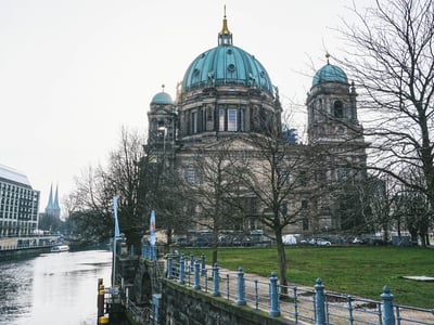 Berliner Dom avec ses dômes verts, bordé par la rivière et des arbres, symbolise l'architecture majestueuse de Berlin.
