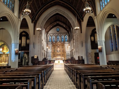 Intérieur de l'église Saint James à New York, montrant l'autel orné et les bancs en bois dans un cadre majestueux.