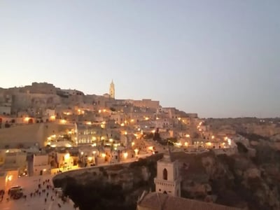 Vue nocturne de la Chiesa San Pietro Barisano surplombant la ville illuminée de Matera, mettant en valeur son architecture unique.
