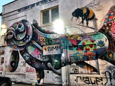 Mur coloré sur le RAW-Gelände à Berlin, représentant un poisson stylisé et une abeille, mettant en avant l'art urbain vibrant.