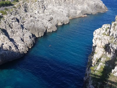 Peaceful bay in Gagliano del Capo with rocky cliffs, turquoise waters, and the deep blue of the sea.