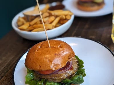 Juicy burger with lettuce, tomato, and onions, served with fries at Bare Burger, relaxed and tasty atmosphere.