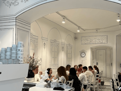 Interior of the 2D Café Always Together with customers chatting around tables, decorated with white artistic patterns.