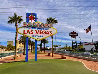 Panneau emblématique "Bienvenue à Las Vegas", entouré de palmiers, représentant l'entrée de la ville du divertissement.