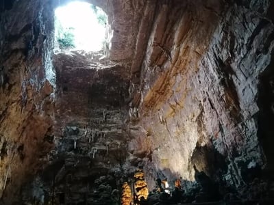 Cavité spectaculaire des grottes de Castellana, avec un puits de lumière illuminant les formations rocheuses uniques.