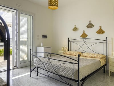 Bright room at Villa Rosaria, featuring a metal bed, modern decor, and access to a balcony.