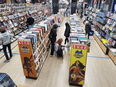 Allées de Midtown Comics avec des clients explorant des bandes dessinées parmi des étagères bien remplies, ambiance animée et conviviale.