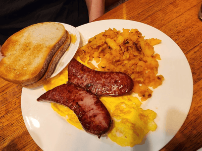 Saucisses grillées accompagnées d'œufs brouillés, de pommes de terre rissolées et de pain grillé, typiques de Little Poland.