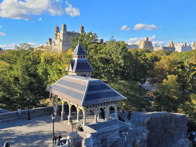 Belvedere Castle overlooking an elegant gazebo with trees and a blue sky in the background, showcasing the beauty of Central Park.