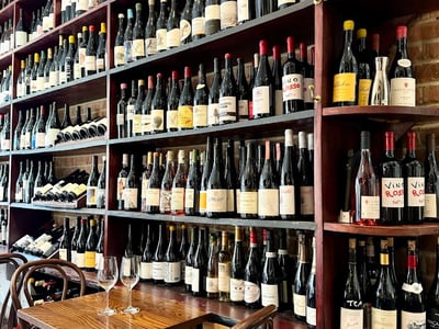 Vitrine de vins raffinés au restaurant The 10 Cases, avec table en bois et deux verres à l'avant.