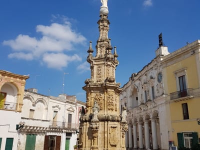 Fontaine baroque emblématique de Nardò, entourée d'architecture historique et d'un ciel bleu, symbolisant le patrimoine local.