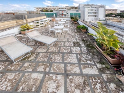 Terrasse spacieuse avec chaises longues et tables, parfaite pour se détendre à ILICE B&B, offrant une vue apaisante.