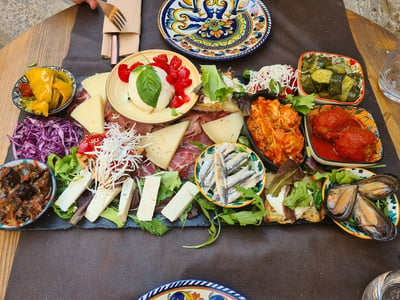 Une planche de charcuterie colorée avec fromages, légumes marinés et salade, servie au restaurant Miro.