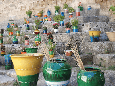 Vases colorés et plantes ornant des marches en pierre dans le Quartier de la céramique, illustrant l'artisanat local.