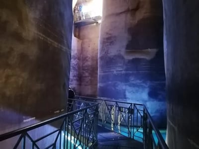 Passerelle métallique à l'intérieur de Palombaro Lungo, révélant des parois de roche illuminées par une lumière naturelle.