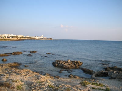 Côte rocheuse à Torre San Giovanni, avec une vue panoramique sur la mer turquoise et le ciel bleu clair.