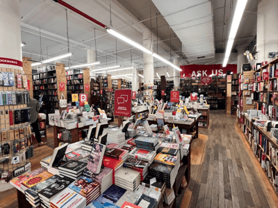 Un intérieur accueillant de Strand Bookstore, rempli de livres soigneusement présentés sur des étagères en bois, créant une atmosphère chaleureuse.
