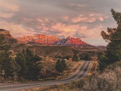 Montagnes colorées au coucher de soleil à Zion National Park, avec une route serpentant à travers la vallée verdoyante.