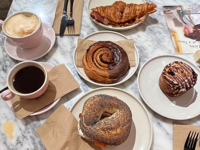 Fair Shot coffee with a selection of pastries, black coffee, and a croissant on an elegant marble table.