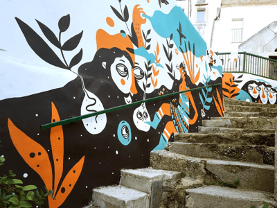 Fresque colorée d'un mur à Rione Civita, illustrant des personnages et des motifs végétaux vibrants.