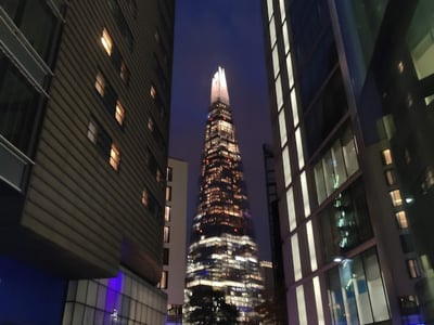 Night view of the illuminated Shard, framed by modern buildings in Southwark, a symbol of London architecture.