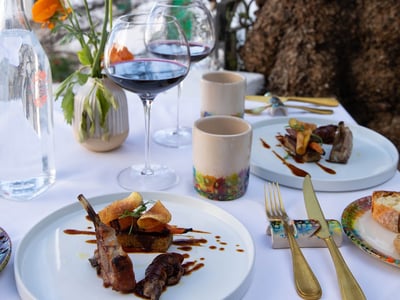 Delicious gourmet dish served with red wine, on an elegant table at Taverna della Gelosia. Flowers as decoration.