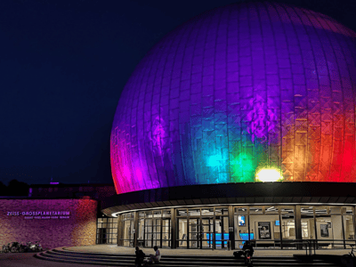 Zeiss planetarium illuminated at night with vibrant colors, offering a magical astronomical experience in Berlin.