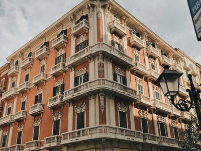 Historic building in Taranto with ornate balconies, reflecting classic Italian architecture under a cloudy sky.