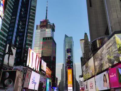Vue animée de Times Square, illuminée par des panneaux publicitaires colorés et des gratte-ciels, symbole de la vie urbaine.