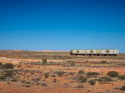 A freight train crossing the arid landscape of Coober Pedy, a symbol of mining in Australia.