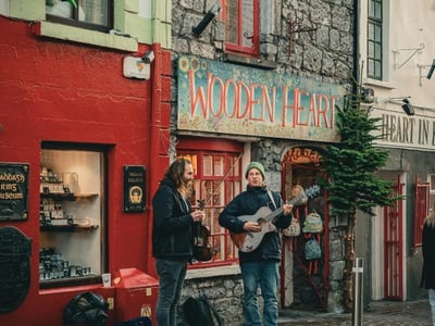 Musiciens de rue interprétant une mélodie devant la boutique Wooden Heart à Galway, créant une atmosphère artistique.