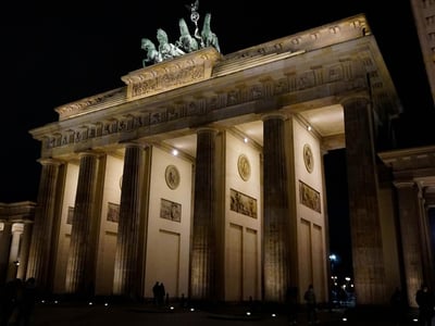The Brandenburg Gate, illuminated at night, symbolizes the history and unity of Berlin with its impressive architecture.