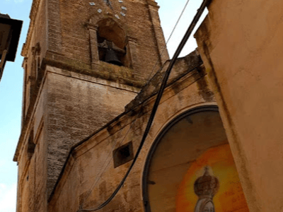 View of the Church of San Domenico with its majestic bell tower and a colorful fresco on the wall, reflecting local art.