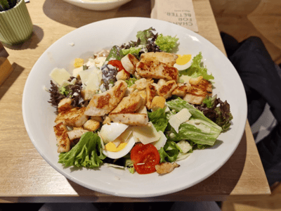 Salade fraîche garnie de poulet grillé, œufs et légumes, dégustée chez dean&david dans un cadre convivial.
