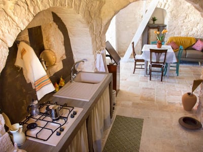 Cuisine confortable de Trullo Sweet Trullo, avec un évier en pierre et une table accueillante pour des repas en famille.