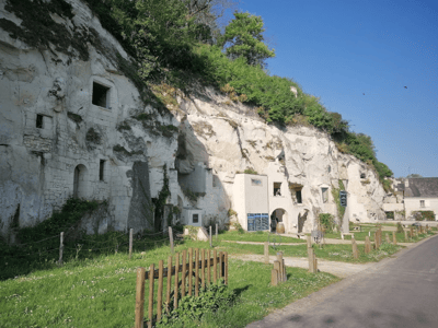 Façade de maisons troglodytes à Turquant, entourée de verdure et de falaises blanches, illustrant l'architecture locale.