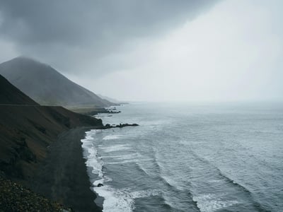 Wild coast of Achill Island with crashing waves under a cloudy sky, evoking the natural beauty of Ireland.