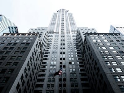 View from below of the Chrysler Building in New York, highlighting its Art Deco architecture and American flag.