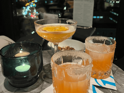 Refined cocktails on a table at Rooftop One Alexanderplatz, with a sparkling nighttime view of Berlin.