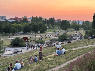 Visitors enjoying a summer evening at Mauerpark, Berlin, with people gathering for outdoor activities.