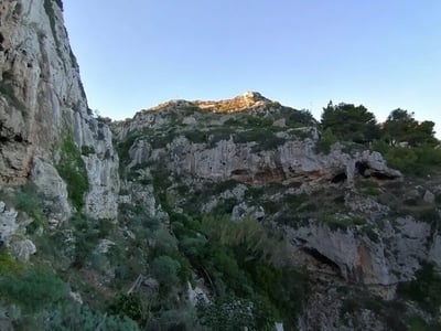 Verdant cliffs of Il Ciolo under a blue sky, offering a natural and preserved panorama of the region.