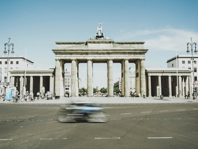 The Brandenburg Gate, an iconic symbol of Berlin, attracts passersby and cyclists under a clear sky.