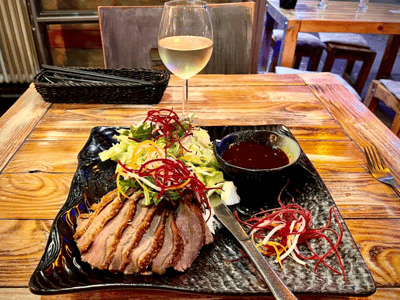 Plat de viande rôtie accompagné de salade fraîche et vinaigrette, avec un verre de vin à Cao Cao.