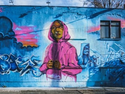Colorful mural of a woman in a pink sweatshirt, located at Haus Schwarzenberg, celebrating urban art and creativity.