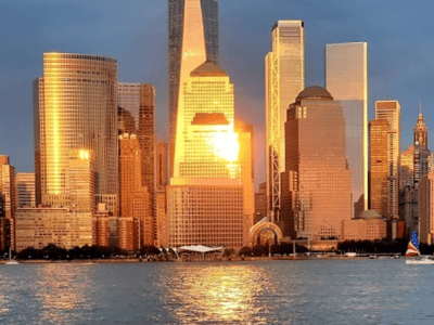 Bright sunrise over the Midtown Manhattan skyline, illuminating the modern skyscrapers and the Hudson River.