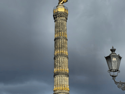 Column of Victory in Berlin, adorned with a golden angel, symbol of peace and victory, under a cloudy sky.