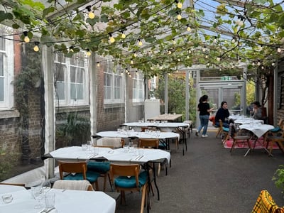 Lush terrace of Rochelle Canteen with elegant tables, soft lighting, and a friendly atmosphere for outdoor dining.