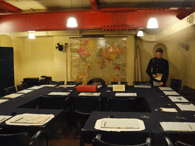 Salle de guerre de Churchill avec des cartes géographiques et des bureaux, évoquant la stratégie militaire historique.