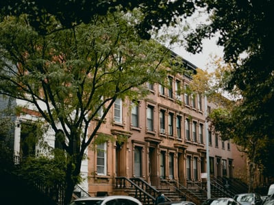 Classic brownstone façade in Harlem, surrounded by trees, illustrating the typical architecture of the neighborhood.