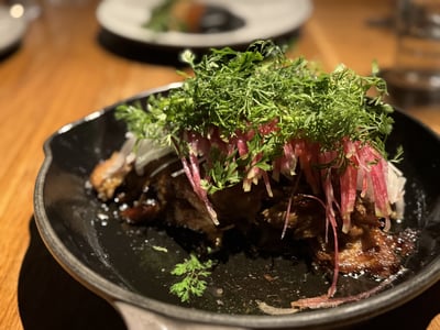 Dish delicately presented with meat garnished with coriander and red onions, offered at the restaurant Cosme.